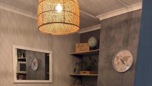 Un salon avec un canapé marron, une table basse, une grande plante verte, une lampe suspendue en osier et une horloge représentant une carte du monde accrochée au mur.
