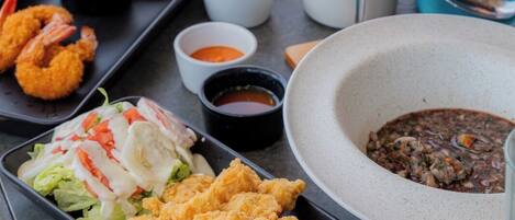 A table with various dishes including fried shrimp, a salad, and a bowl of soup.