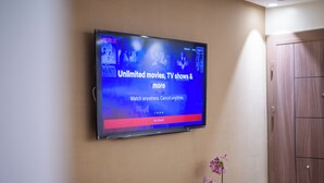 A flat-screen TV mounted on a wall displaying a streaming service interface with options for movies, TV shows, and more. - Apartment with WiFi, Air conditioning, Parking, near Marina, Stadium and Souk (Agadir)