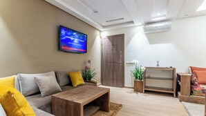 A modern living room with a sofa, coffee table, TV, and a wooden cabinet. - Apartment with WiFi, Air conditioning, Parking, near Marina, Stadium and Souk (Agadir)