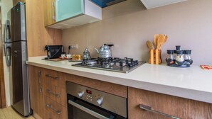 A modern kitchen with a stainless steel refrigerator, a gas stove, and wooden cabinets. - Apartment with WiFi, Air conditioning, Parking, near Marina, Stadium and Souk (Agadir)