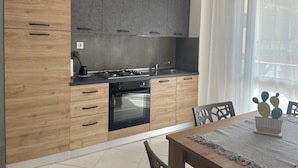 A modern kitchen with wooden and grey cabinets, a built-in oven, and a dining area with a table and chairs. - Soul of Sal | 2-Bedroom, 2-Bathroom Central Apartment with Wi-Fi and A/C (Santa Maria)