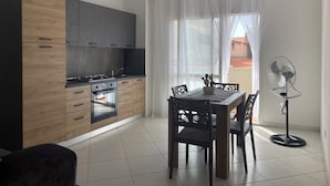 A modern kitchen with a dining area, featuring a table with chairs, a fan, and a view of the outside. - Soul of Sal | 2-Bedroom, 2-Bathroom Central Apartment with Wi-Fi and A/C (Santa Maria)