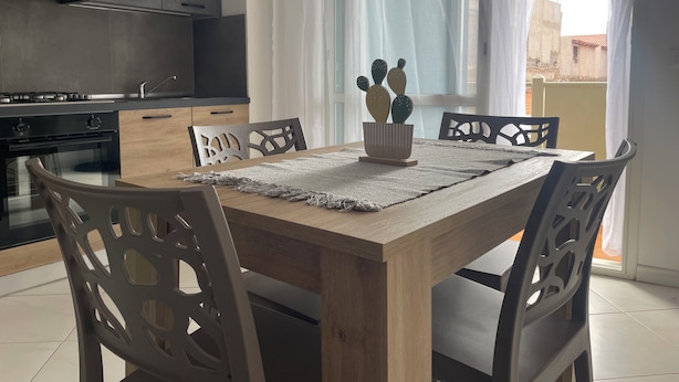 A modern kitchen with dark cabinets, a wooden dining table, and chairs. - Soul of Sal | 2-Bedroom, 2-Bathroom Central Apartment with Wi-Fi and A/C (Santa Maria)