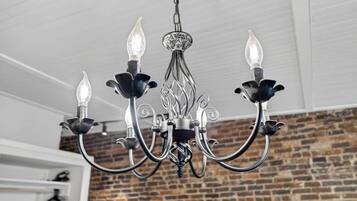 Un candelabro con una ornamentada estructura metálica central y cuatro brazos, cada uno con una bombilla al final.