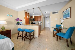 A kitchen with a central island, bar stools, a dining table with chairs, and a kitchen island with a microwave and oven.