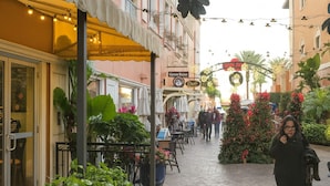 Un espace de café en plein air avec des tables et des chaises, un sapin de Noël et un bâtiment sur lequel on peut lire l’inscription « Café Room ».