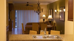Une cuisine dotée de plans de travail en granit, d’un évier et d’un coin repas avec une table et des chaises.