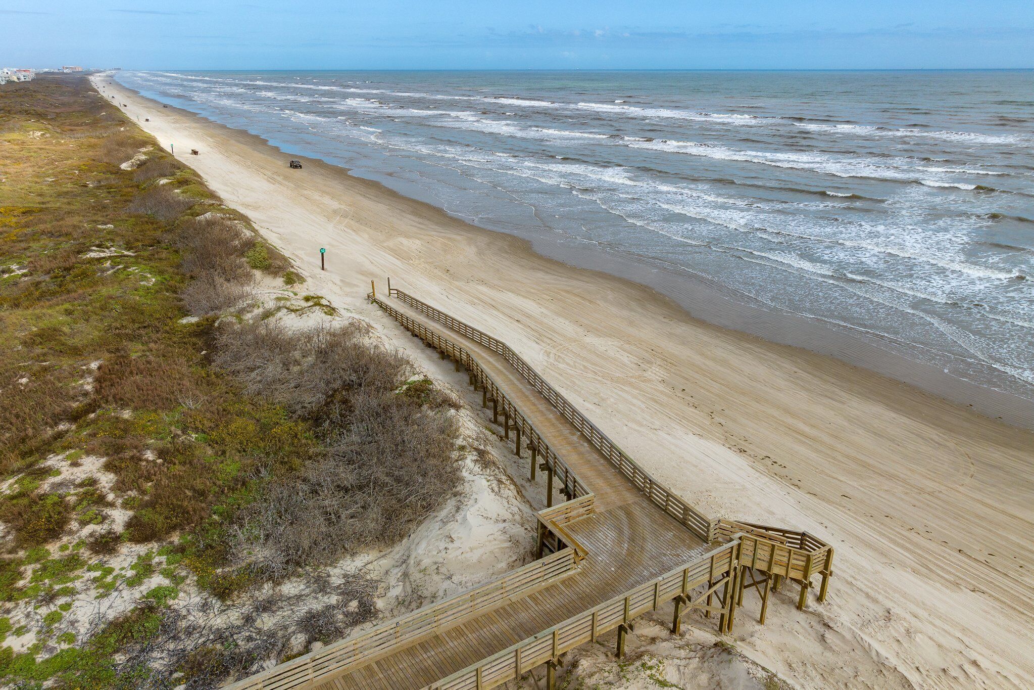 A beach with a wooden boardwalk leading to a sandy area.