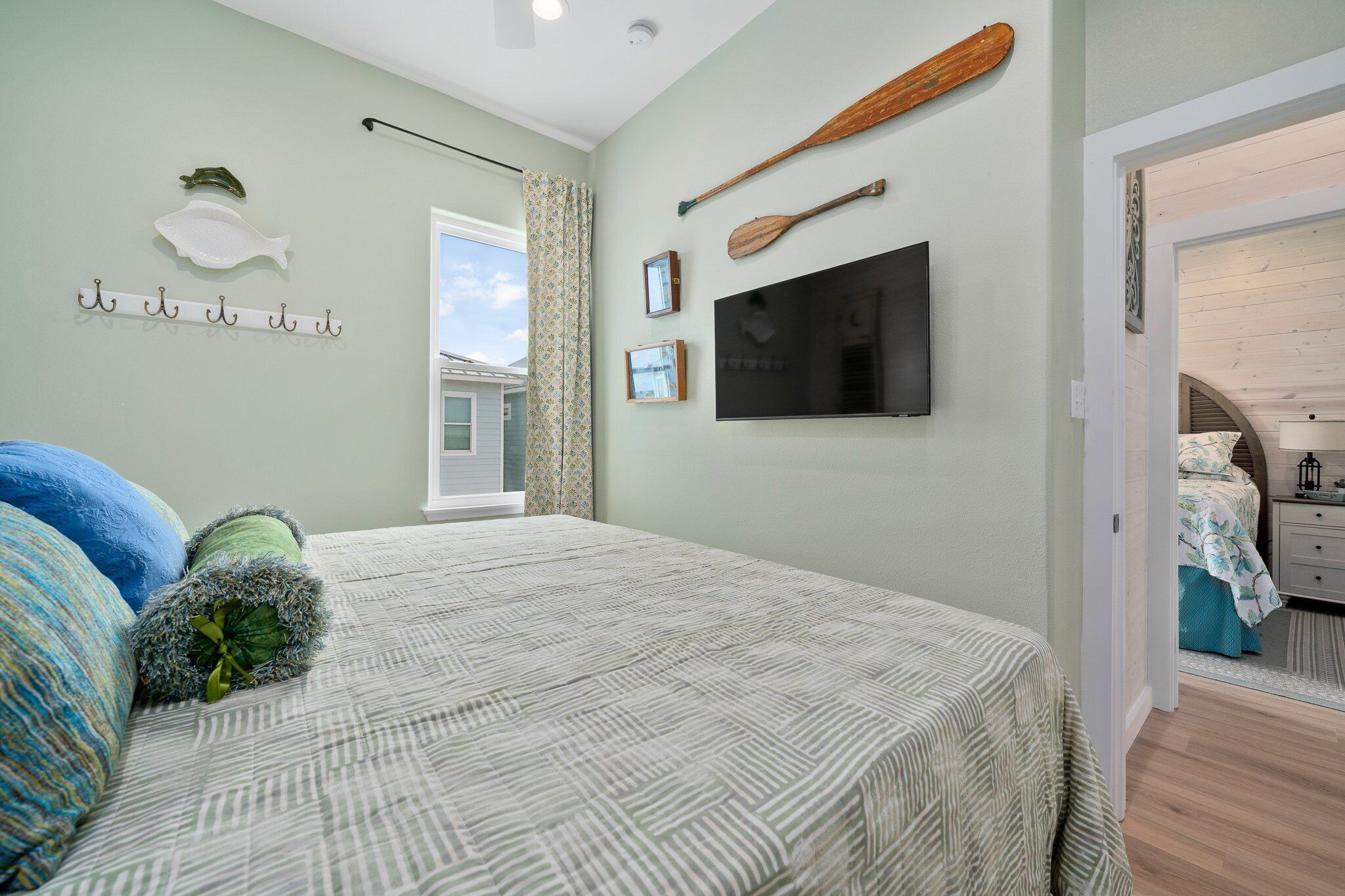 A bedroom with a bed, a television, and a wall-mounted paddleboard.