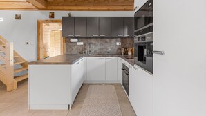 A modern kitchen with white cabinets, a wooden ceiling, and a built-in oven.