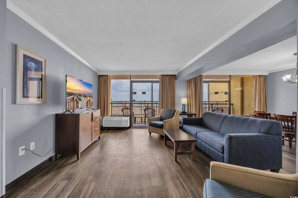 A hotel room with a balcony, a sofa, a desk, and a TV. - Exclusive 2-bedroom condo at Caravelle. (Myrtle Beach)