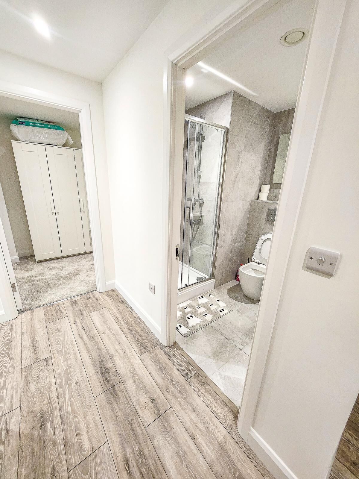 A modern bathroom with a shower, toilet, and storage cabinets.