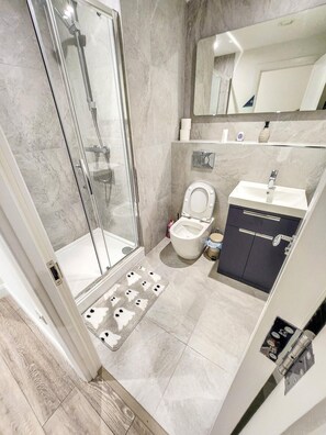 Ein modernes Badezimmer mit Duschkabine aus Glas, Toilette und Waschbecken mit Schrank.