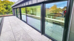 Un bâtiment moderne doté de grandes fenêtres en verre et d’une terrasse-toit à surface plane.