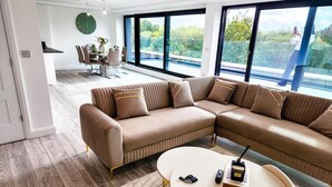 Un salon moderne avec un canapé d’angle, une table basse ronde et un coin repas comprenant une table et des chaises.