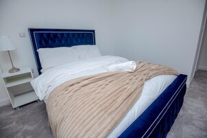 A neatly made bed with a blue headboard and a beige blanket.