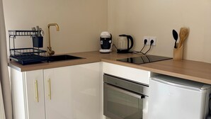 Eine moderne Küche mit weißen Schränken, einem Einbauofen, einer Kaffeemaschine und einem Wasserkocher.