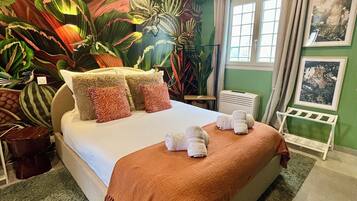 A bedroom with a large bed, green walls, and tropical-themed wallpaper.