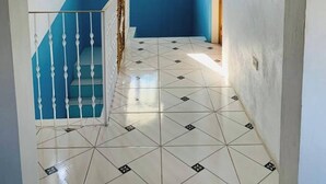 Ein Flur mit blau-weißer Farbgebung, einem gefliesten Boden und einer Treppe mit weißen Spindeln.