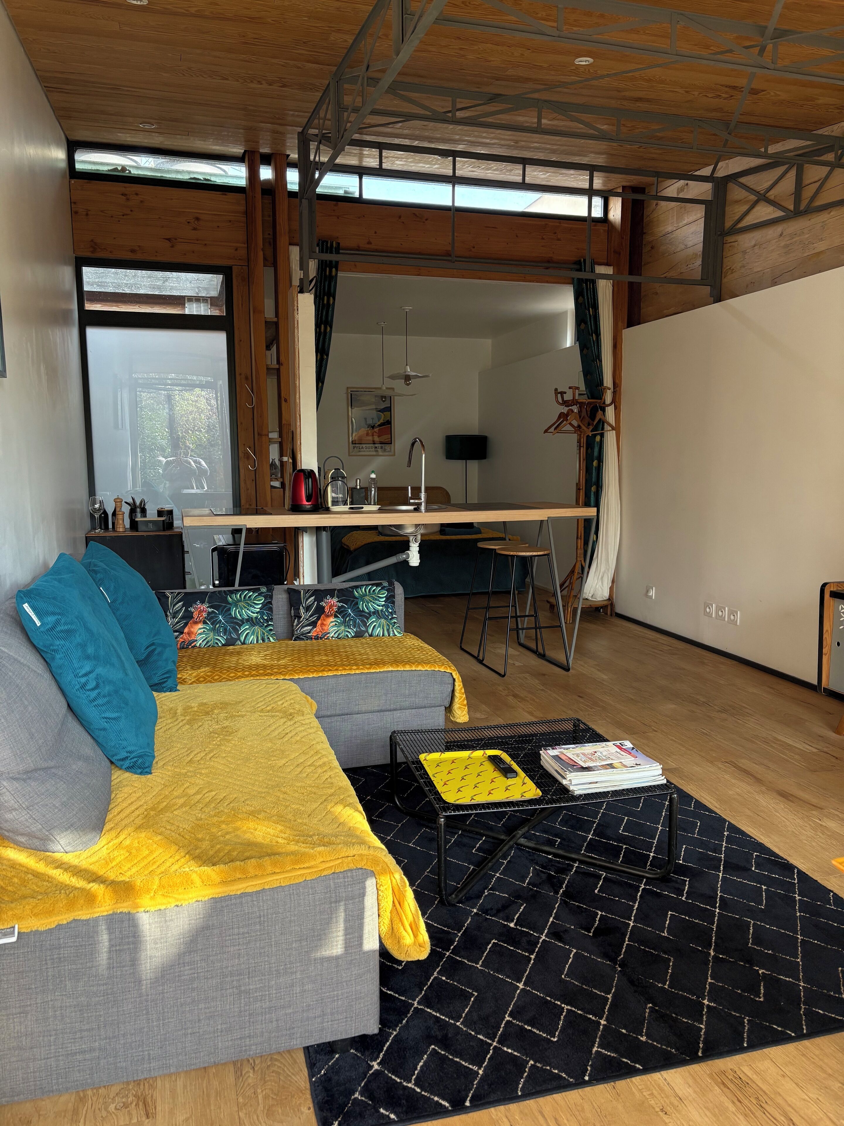 A modern living room with a sofa, a coffee table, and a dining area with a bar.