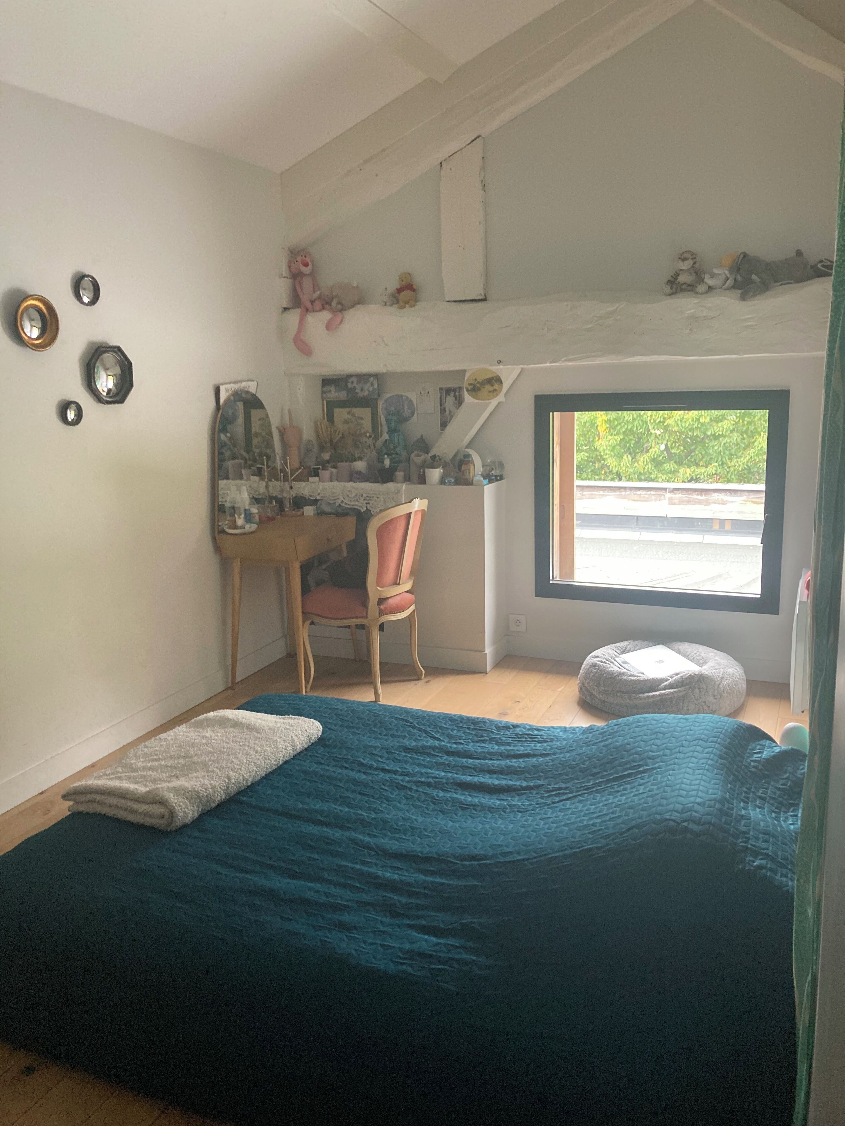 Quarto com cama, escrivaninha, cadeira e janela.