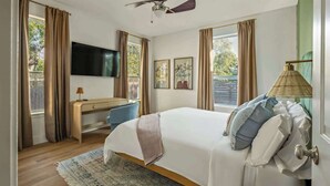 A bedroom with a bed, desk, TV, and curtains. - The Backyard Bliss - 4BR Heated Pool & Ping Pong (Austin)