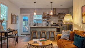 A modern kitchen with a brick backsplash, pendant lights, and a dining area with a round table and chairs. - The Backyard Bliss - 4BR Heated Pool & Ping Pong (Austin)
