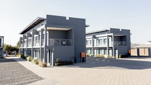 A modern building with a flat roof, multiple balconies, and a paved entrance area. - Khayalami Hotel Secunda (Secunda)