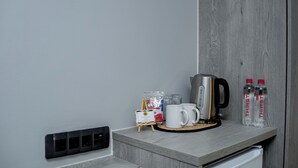 A kitchen counter with a coffee maker, two mugs, a small easel, and two bottles of water. - Khayalami Hotel Secunda (Secunda)