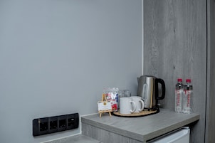 Una encimera de cocina con una cafetera, dos tazas, un caballete pequeño y dos botellas de agua.