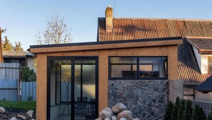 A modern house with a stone facade, large glass doors, and a wooden deck.