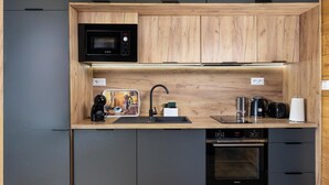 A compact kitchen with a microwave, coffee machine, kettle, toaster, and dishwasher.