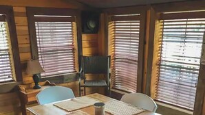 A wooden dining table with four chairs, a lamp, and a chair with a woven seat cushion.