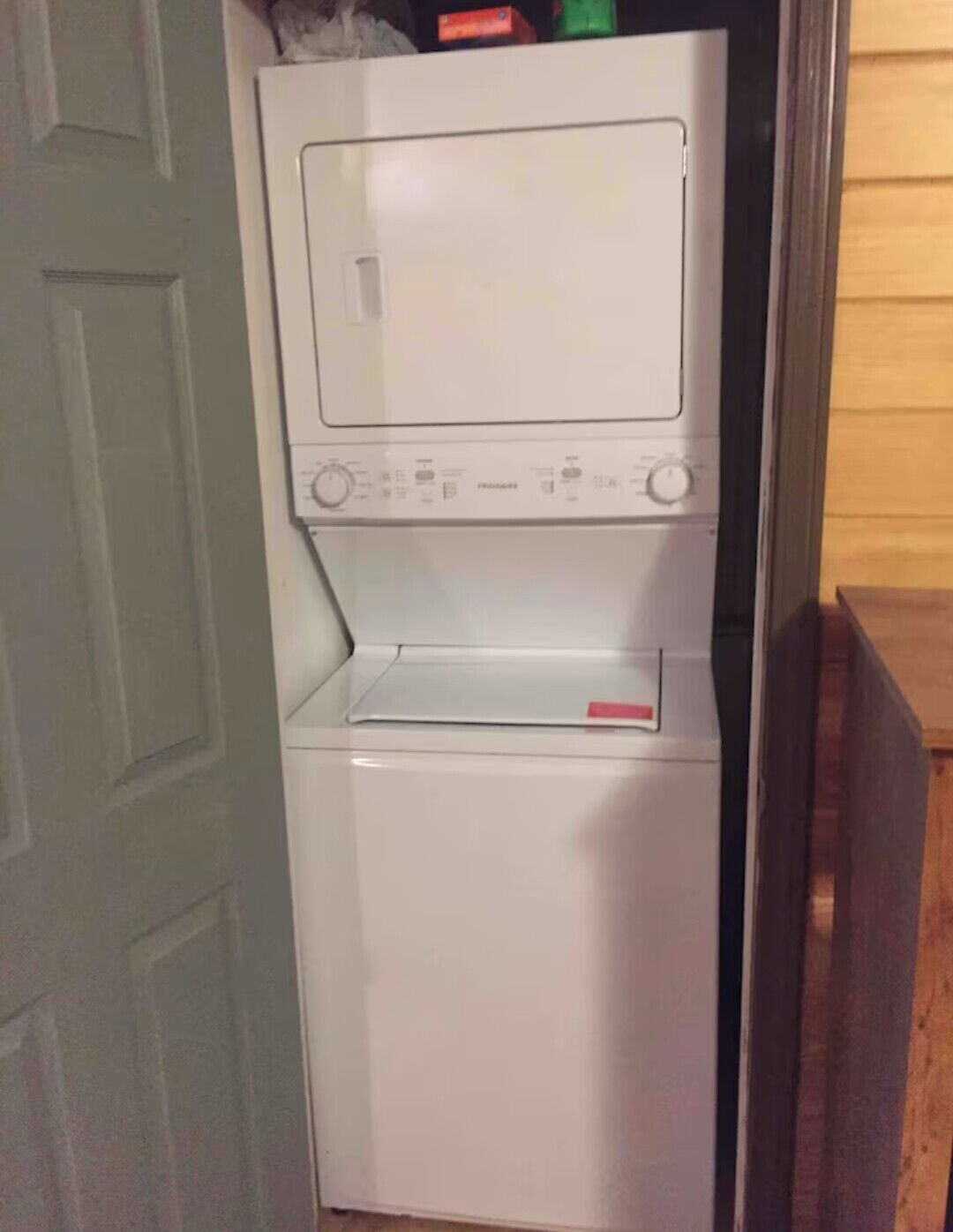 A compact, white, wall-mounted washer and dryer unit with control panels and a small storage compartment.