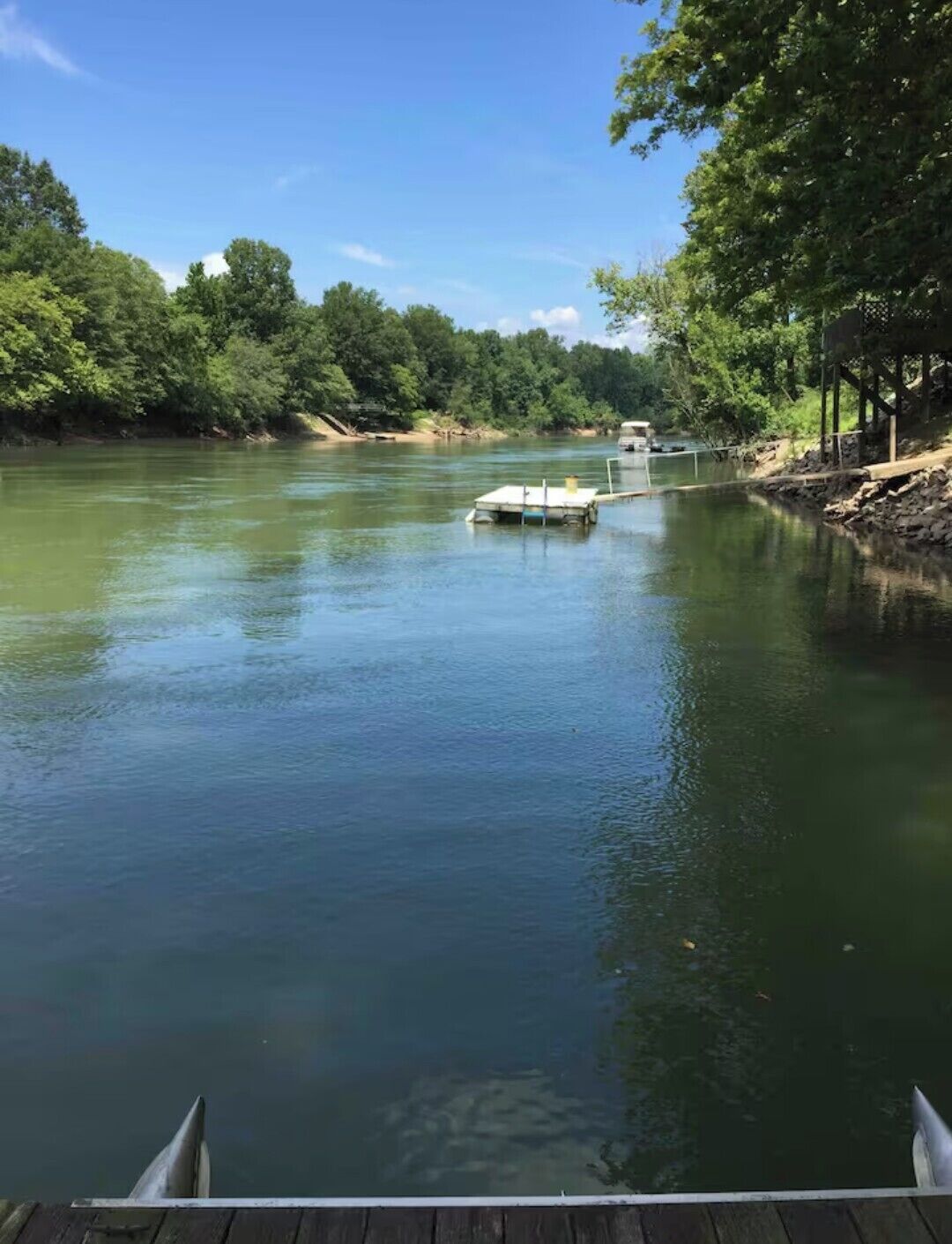 Un río tranquilo con un muelle y un pequeño bote.