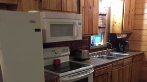 A kitchen with wooden cabinets, a white refrigerator, a microwave, a stove, and a sink.