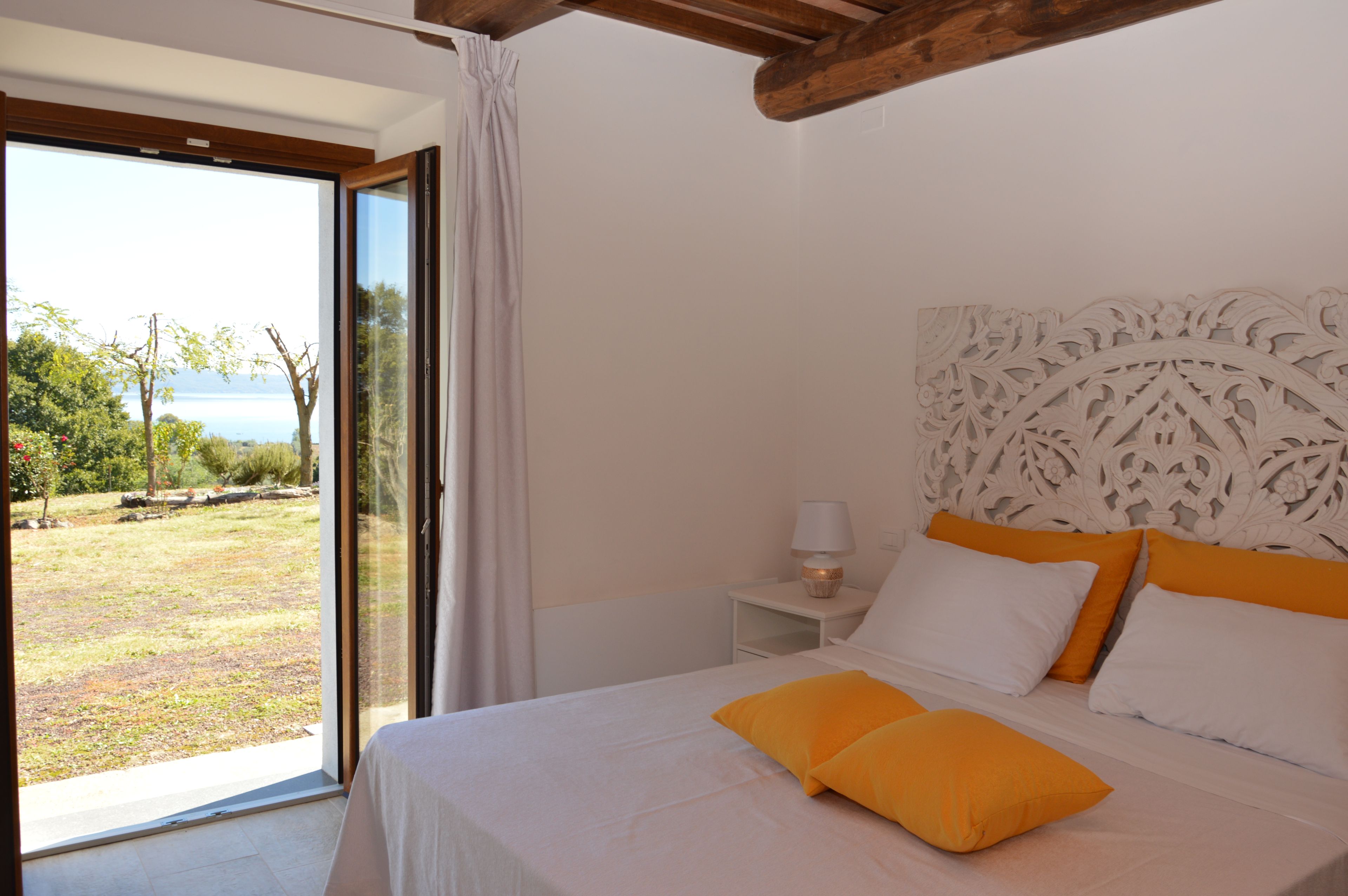 Un dormitorio con una cama, una mesita de noche, una lámpara y vistas al exterior.