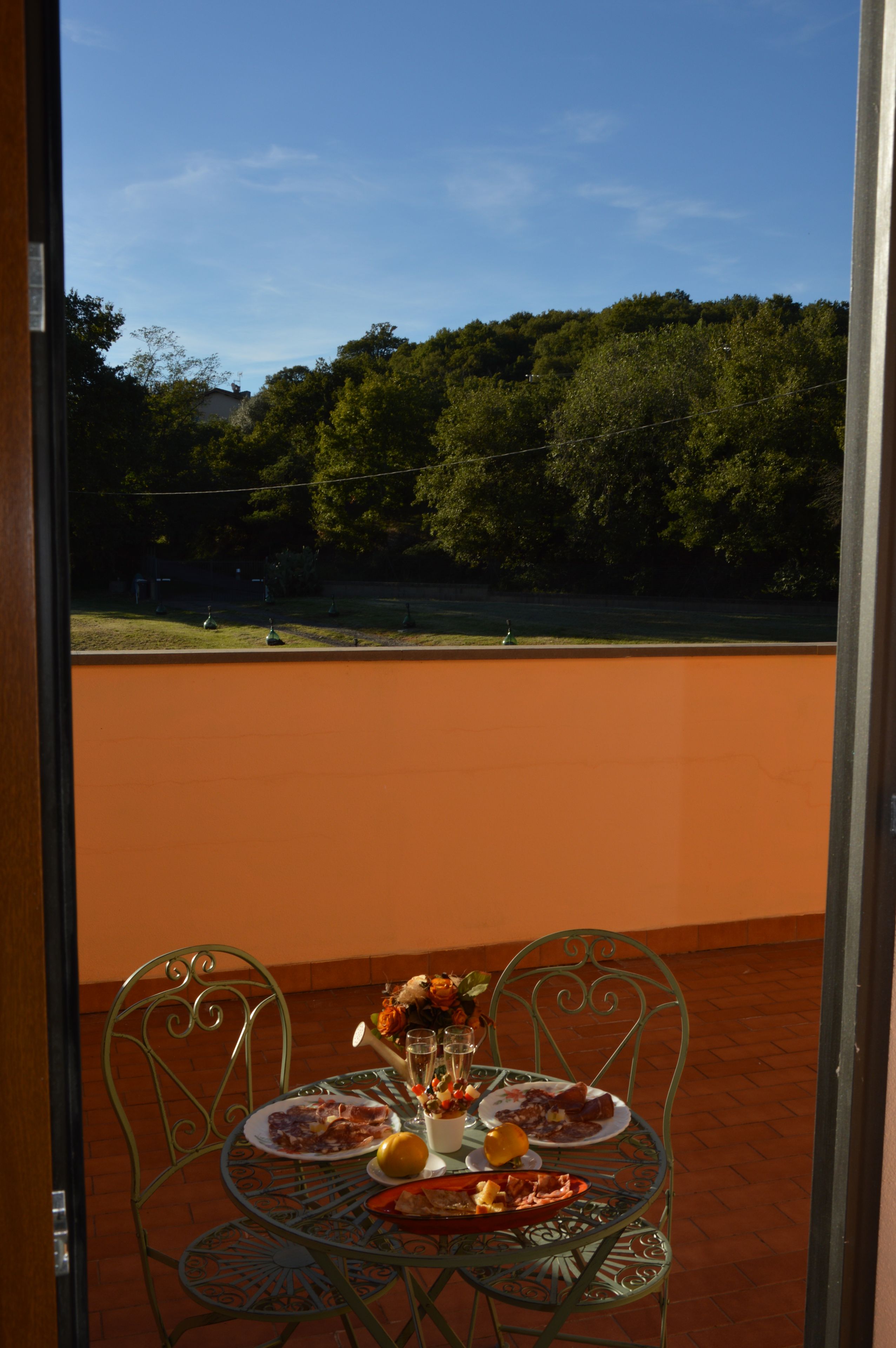 Una mesa con platos de comida y un vaso de agua, con vistas panorámicas al fondo a través de una ventana.
