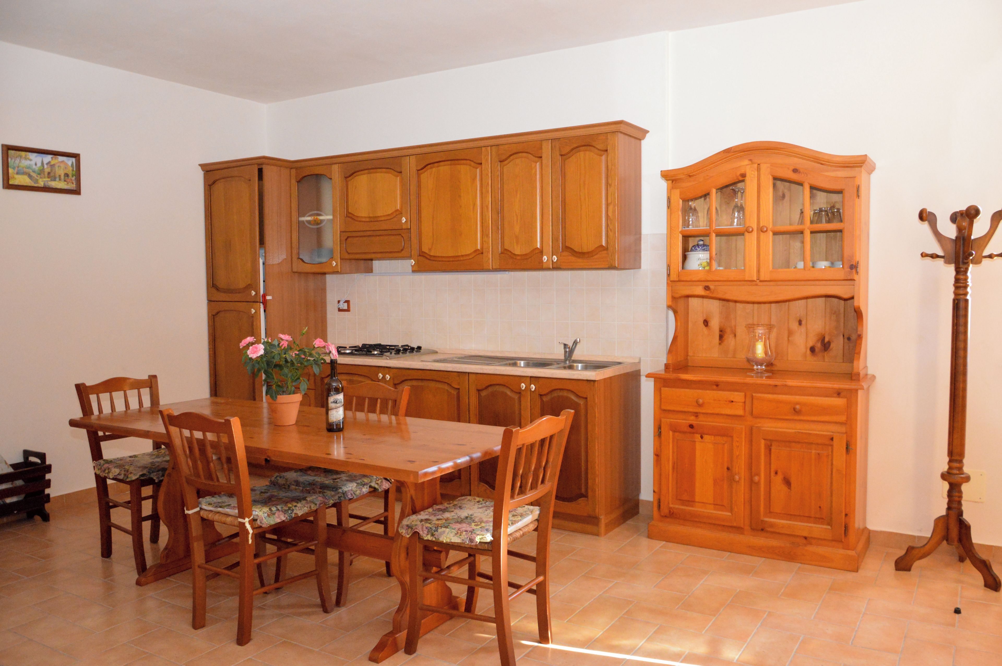 A kitchen with wooden cabinets, a dining table with chairs, and a coat rack.