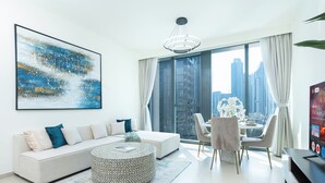 A modern living room with a sofa, round coffee table, and a dining area with chairs and a table.