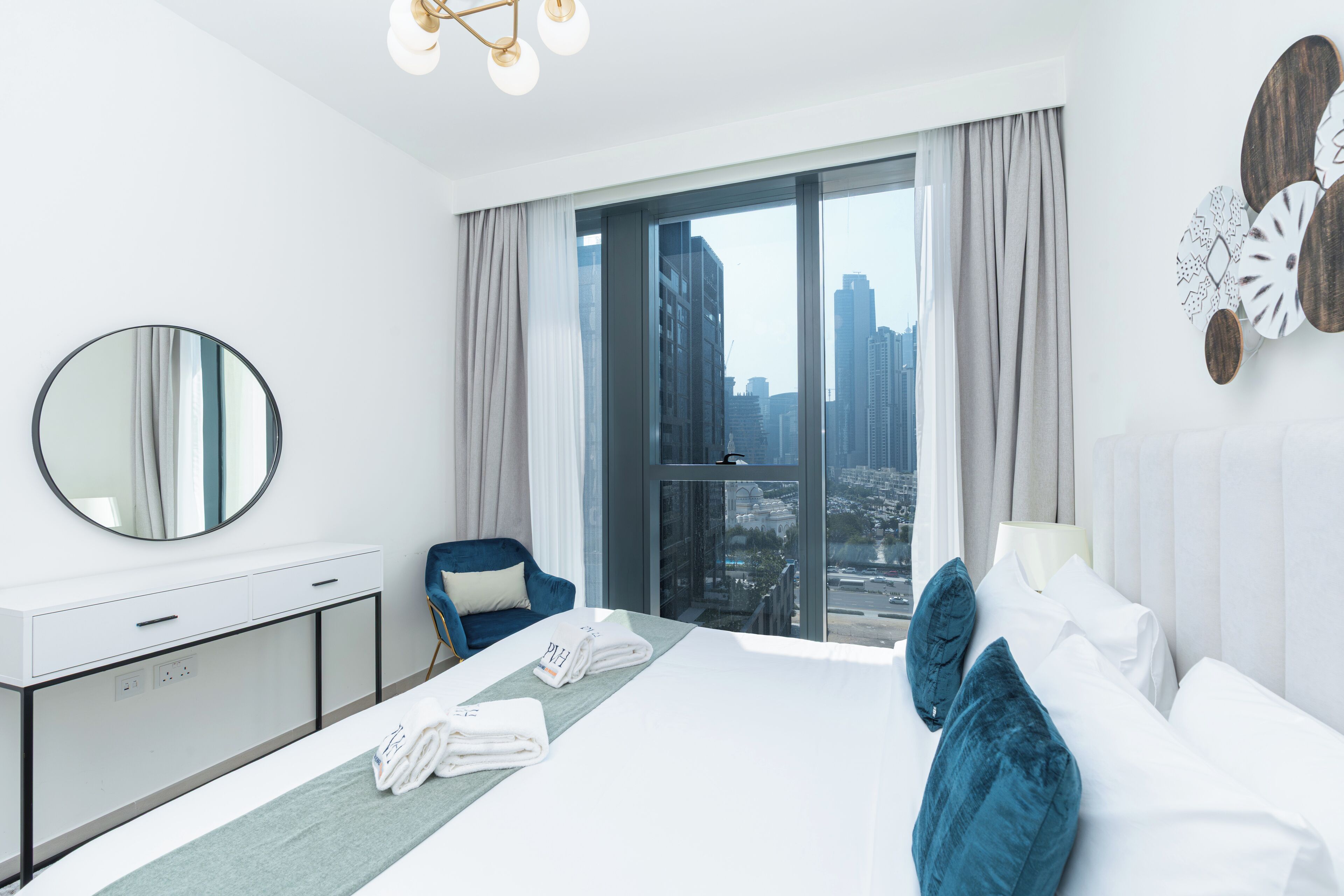 Una camera d'albergo moderna con un letto grande, una scrivania con uno specchio e vista sulla città da una grande finestra.