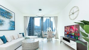A modern living room with a sofa, ottoman, dining table, and TV.