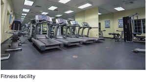 Ein Fitnessstudio mit Laufbändern, Trainingsgeräten und einer Spiegelwand.