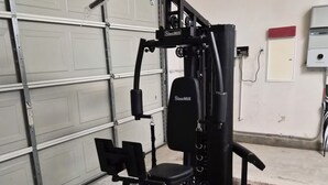 Ein Fitnessraum mit Ergometer, Gewichthecke und Squat-Rack.