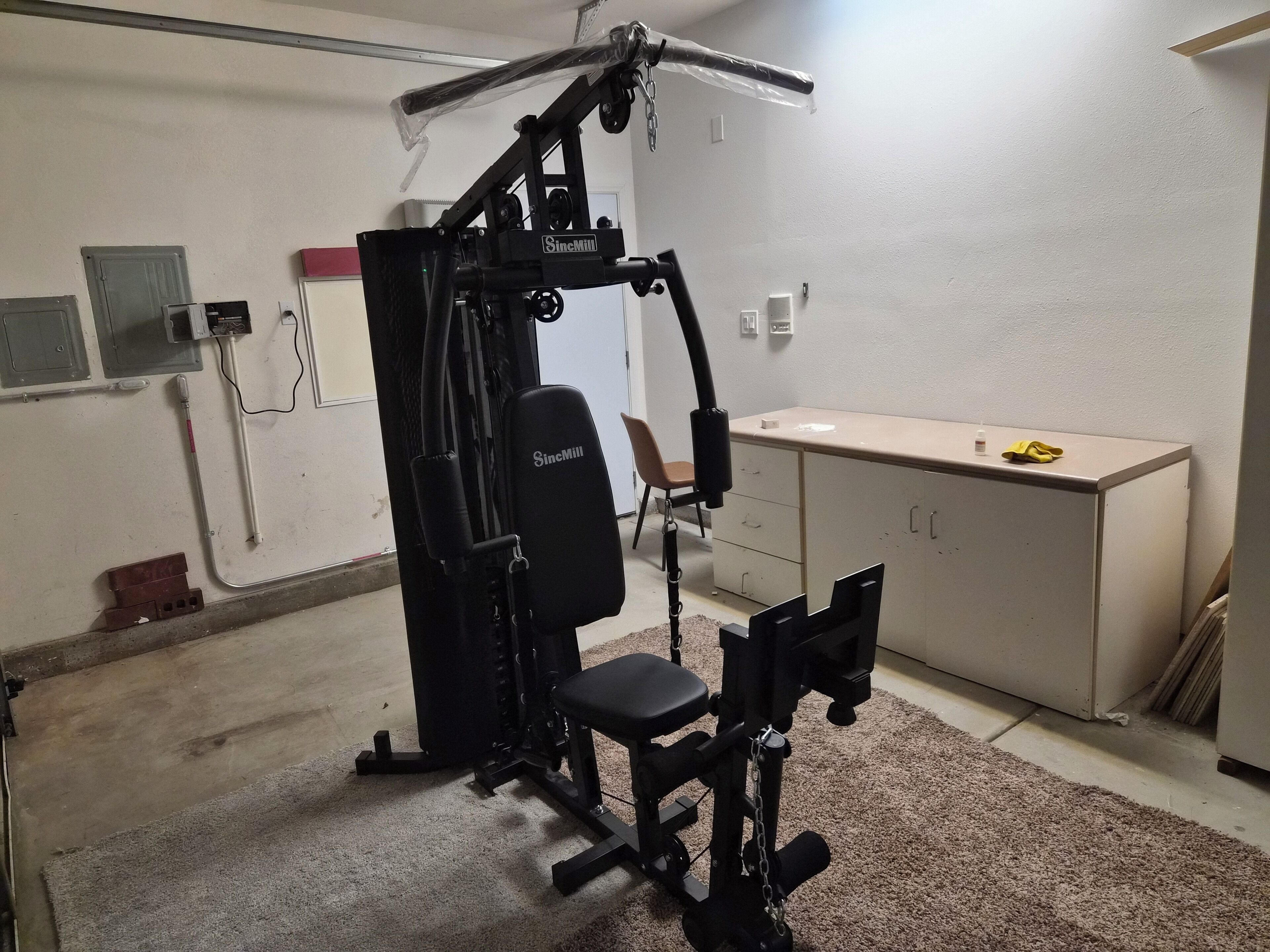 A home gym with a stationary bike, weight bench, and a squat rack.