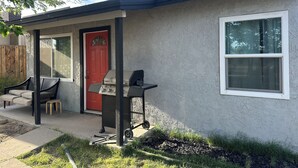 Ein Haus mit roter Tür, Grill und Fenster.