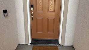 A wooden door with a doormat that reads "HELLO". - New-construction, Pet-Friendly 2-bedroom house in Hanford (Hanford)