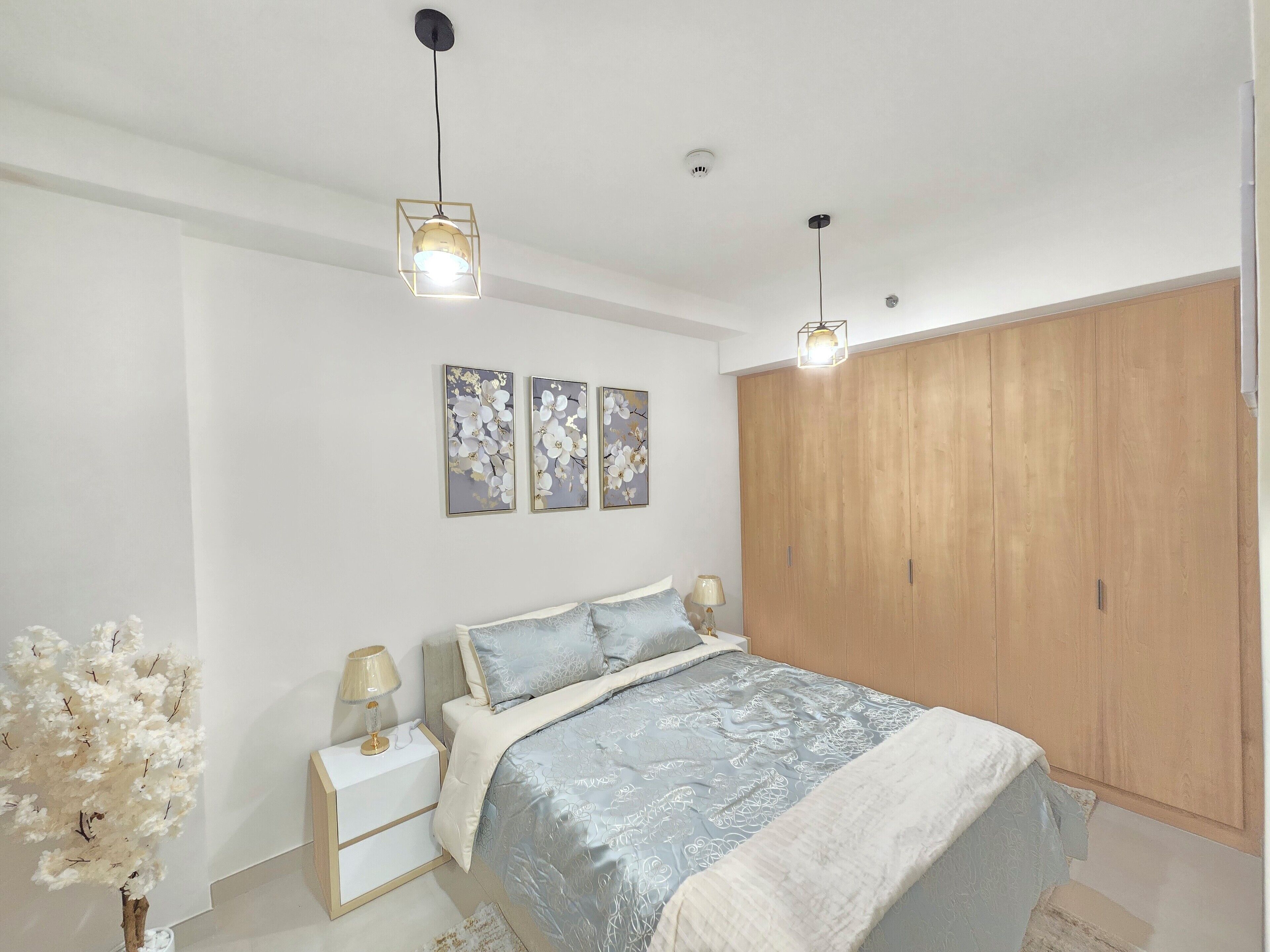 A bedroom with a bed, nightstands, a wardrobe, and decorative elements.