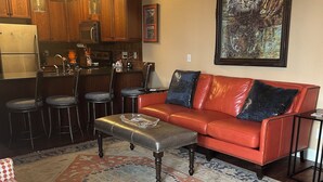 A living room with a red leather sofa, patterned rug, and a tiger painting on the wall. -  3-BR Condo Auburn, AL  Walking distance and minutes from downtown and campus (Auburn)